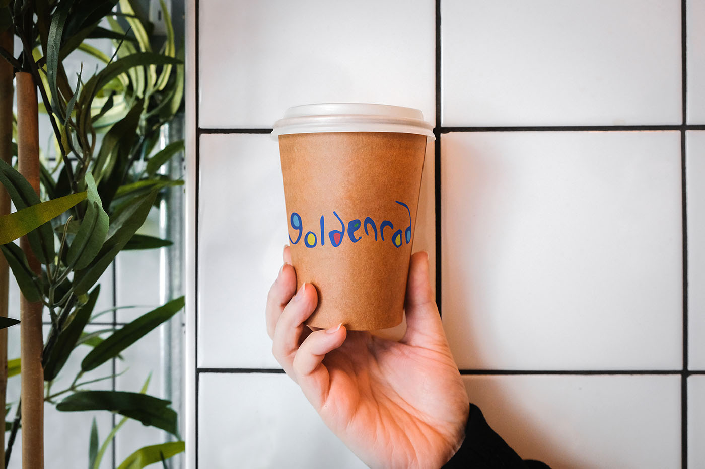 hand holding Goldenrod-branded to-go cup